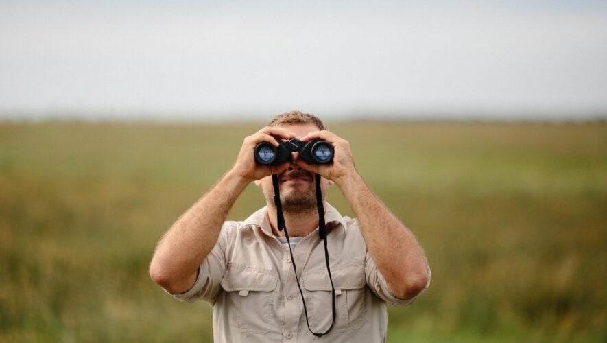 a man in a field with binoculars