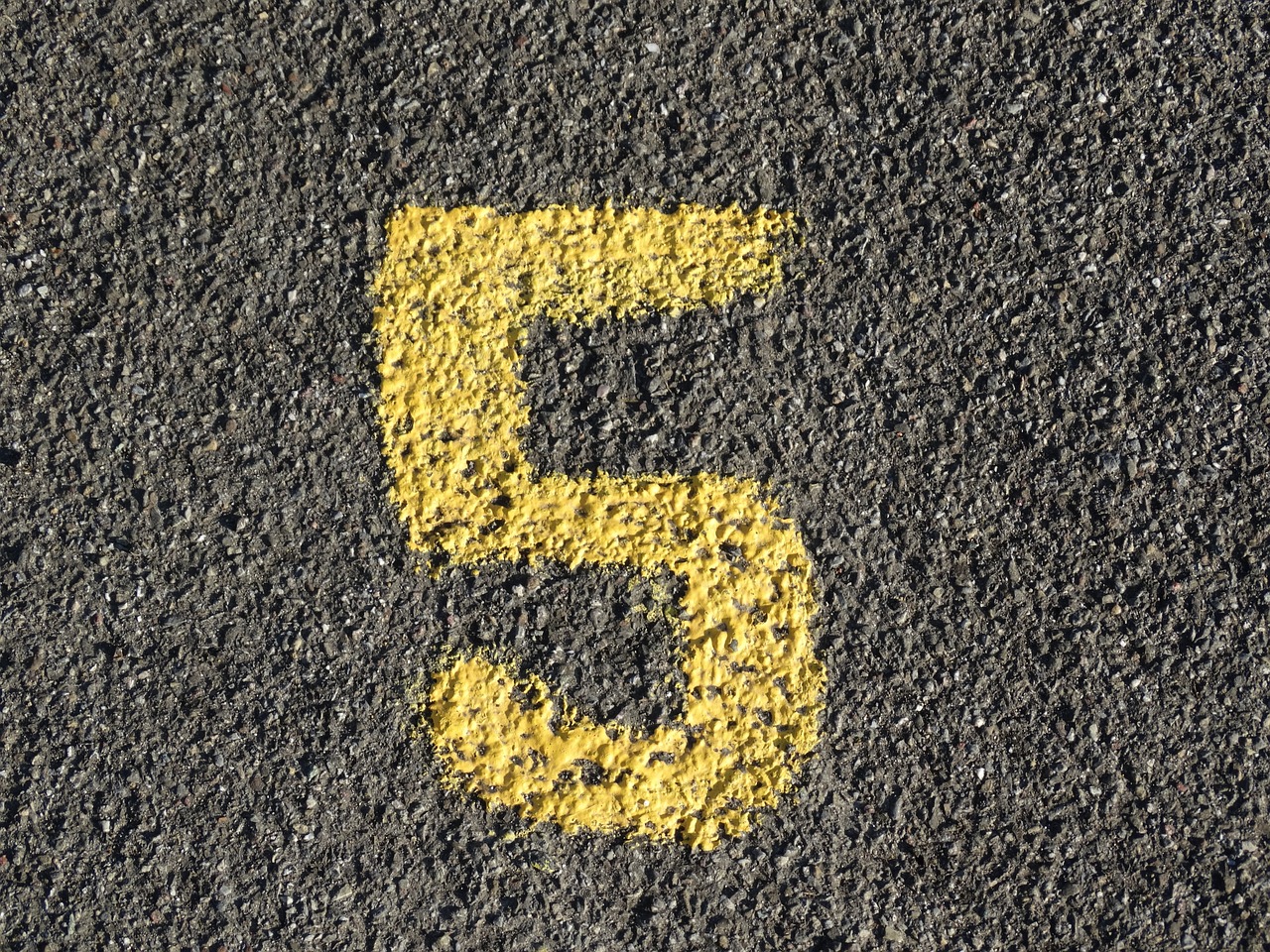 Yellow number five painted on pavement