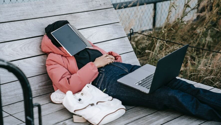 a student taking a nap on a bench